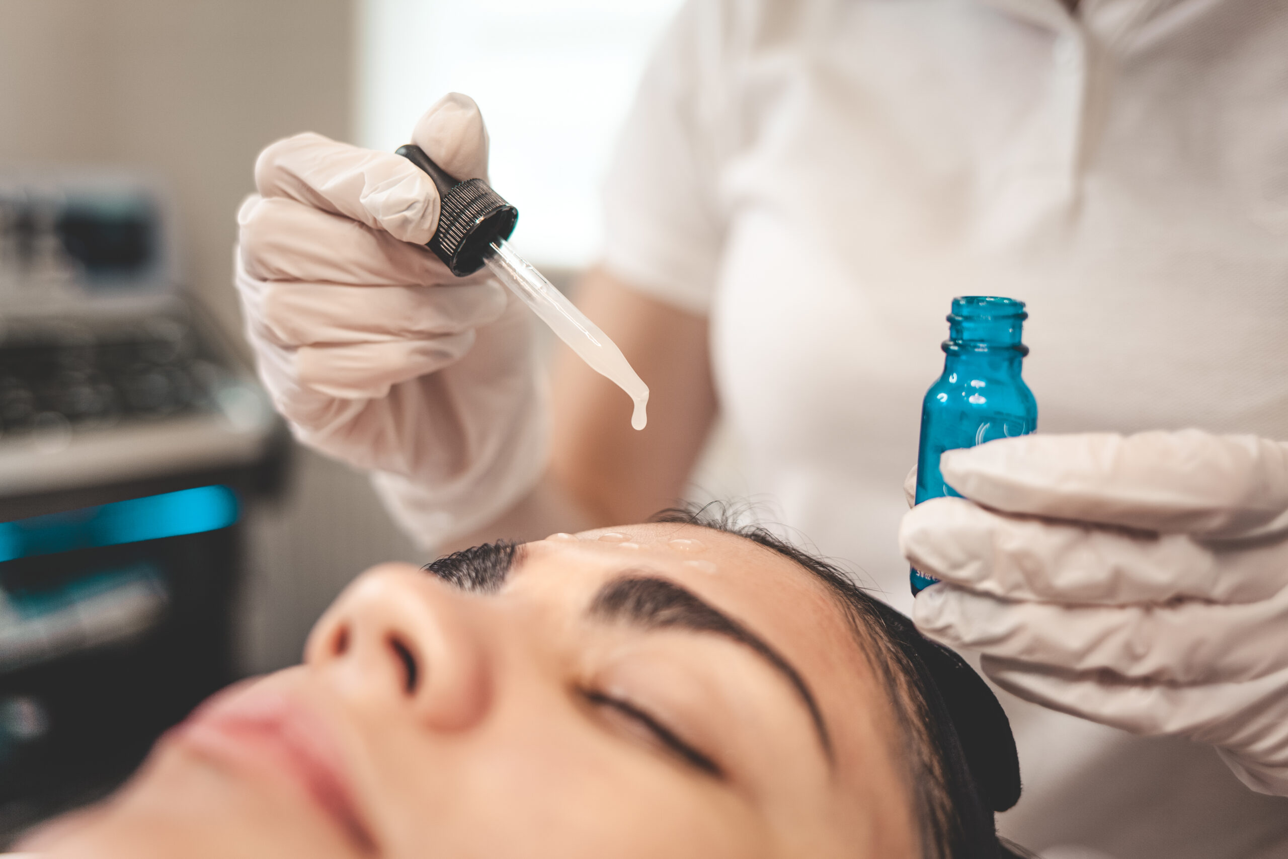 Doctor beautician applies oil to the skin of the face