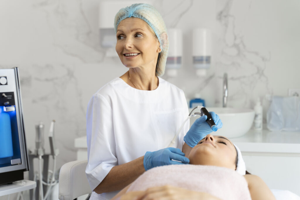 Professional female cosmetologist doing hydra-facial procedure in cosmetology clinic